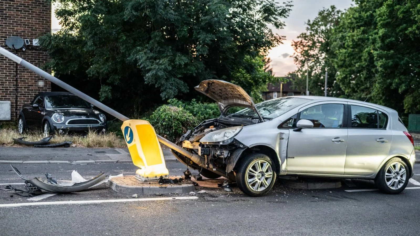 Silberner Kleinwagen mit schwerem Frontschaden nach einem Unfall an einer Verkehrsinsel: Kfz-Gutachter und Kfz-Sachverständiger in der Nähe finden