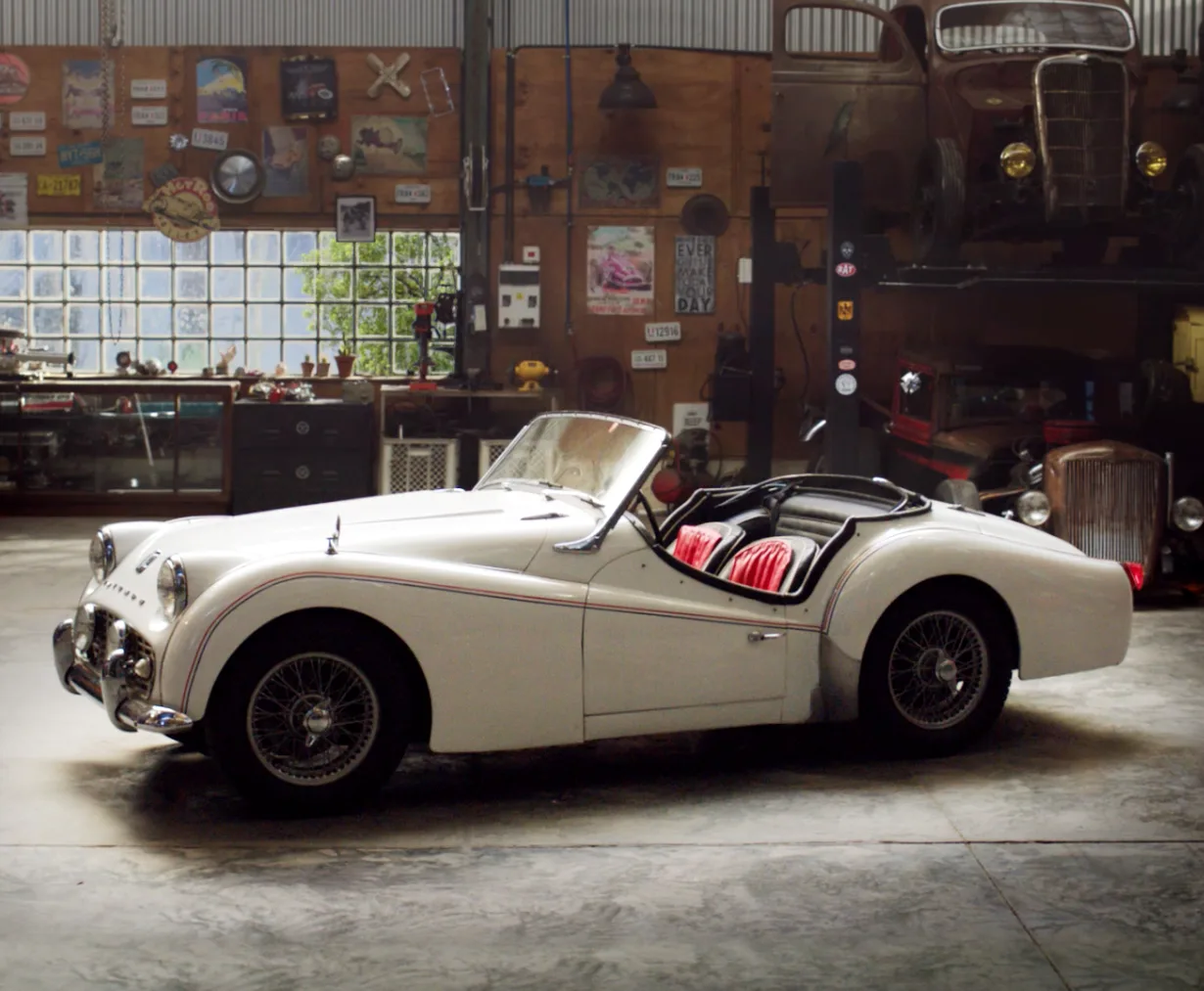 Weißer Oldtimer-Roadster in einer Vintage-Autowerkstatt