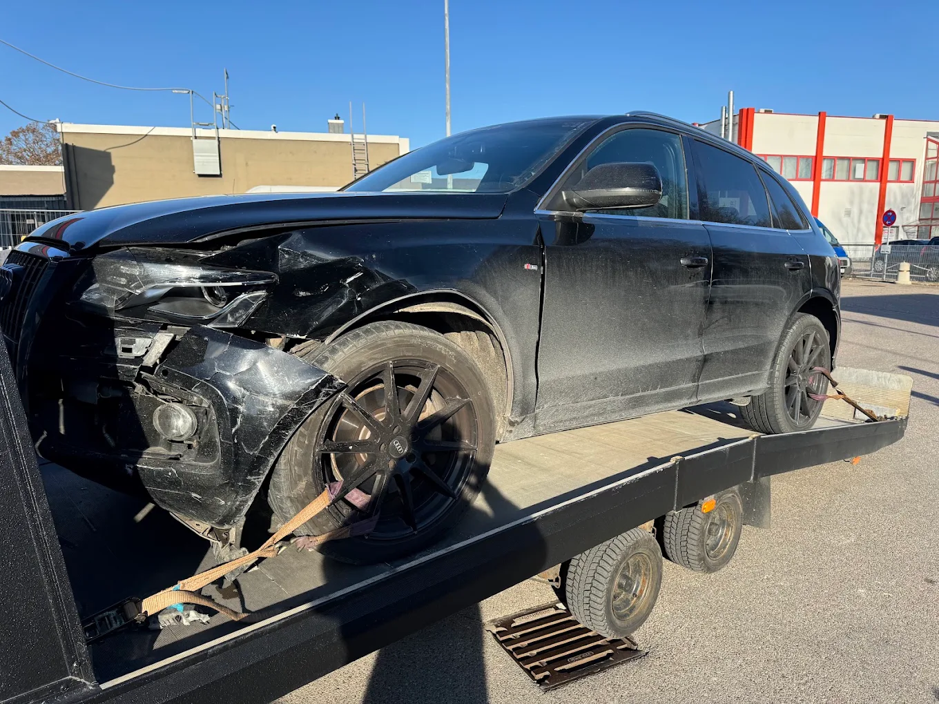 Stark beschädigter schwarzer Audi nach einem Frontschaden auf einem Abschleppwagen